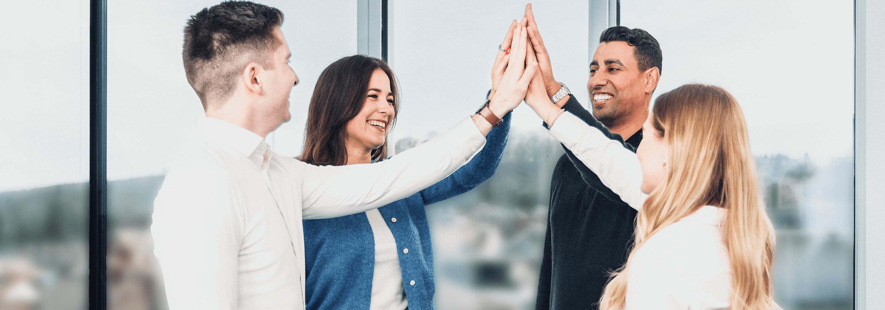 Colleagues high-fiving in an office setting, showing team collaboration and positive work culture.